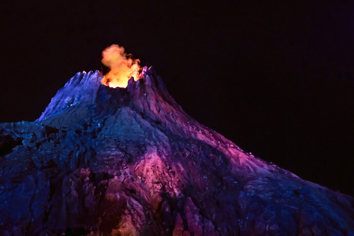Mount Prometheus erupting at night, lit up in blue and pink at Disney Sea