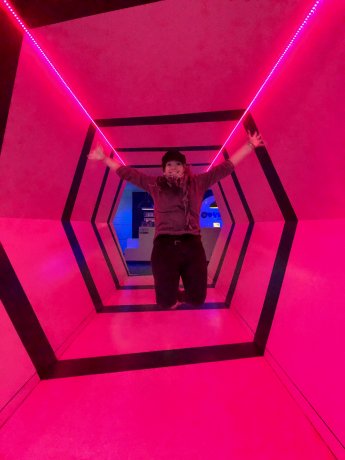 Amelia jumping in a pink lit tunnel with optical illusion