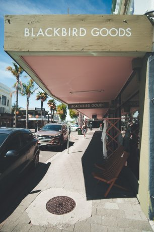 The pale green street signage and frontage of Blackbird Goods in Napier
