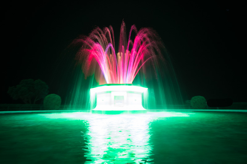 Tom Parker fountain lit up in neon hues at night along Marine Parade