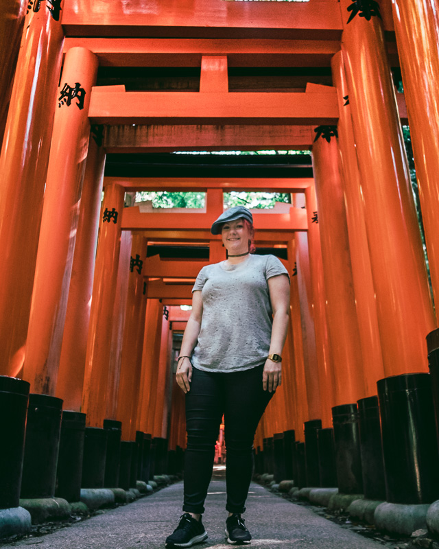 Standing in front of the orange tori gates of Fushimi Inari Shrine in Southern Kyoto